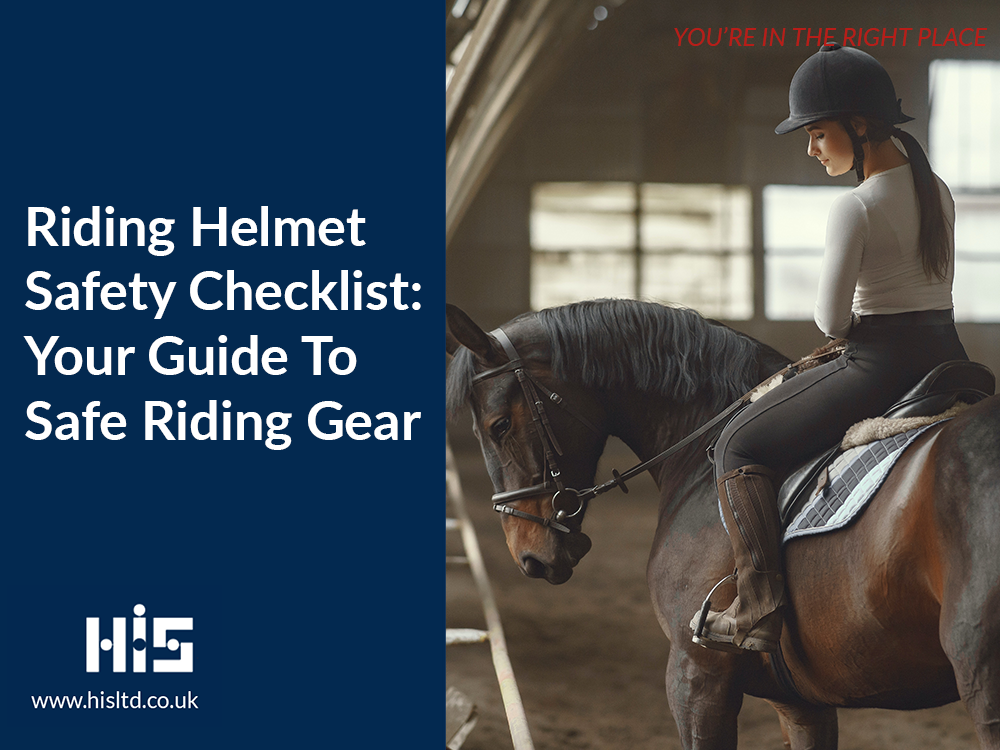 A woman wearing riding gear including a riding helmet, on the saddle of a horse in a stable.